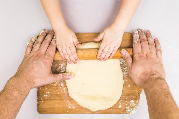 Les enfants et les mains de papa ont roulé la pâte