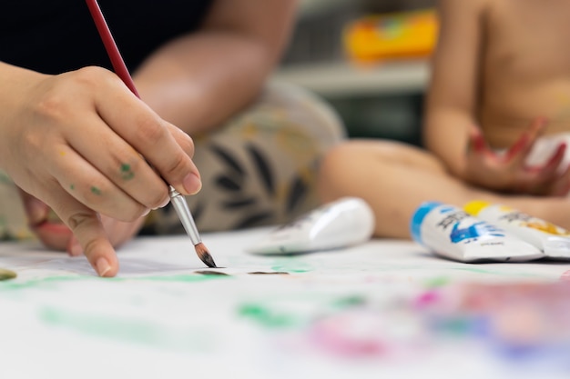 Enfants avec maman peignant des images à l'aquarelle au pinceau