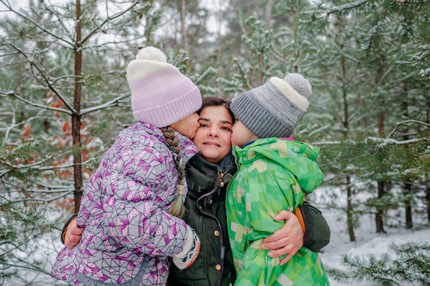 Les enfants avec maman profitent de la première neige dans la forêt d'hiver activités saisonnières actives mode de vie