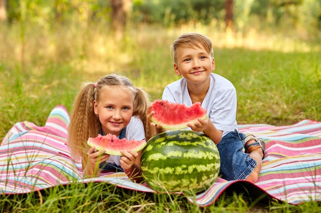 Enfants mangeant de la pastèque dans le parc