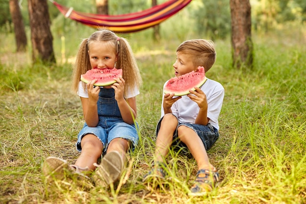 Enfants mangeant de la pastèque dans le parc