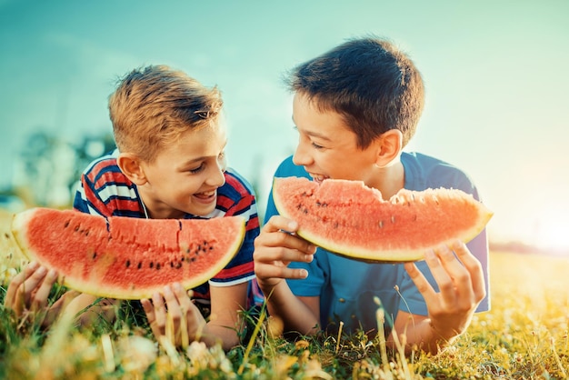 Enfants mangeant de la pastèque dans le parc