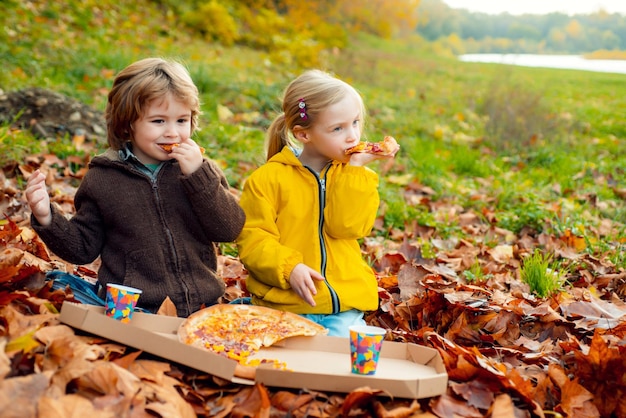 Enfants mangeant de la pizza à l'automne dans la nature