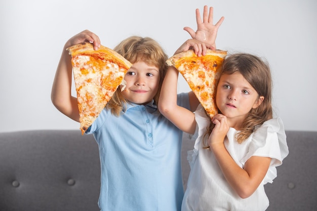 Enfants mangeant de la pizza heureux enfants drôles mangeant de la pizza et s'amusant ensemble enfants drôles tenant p