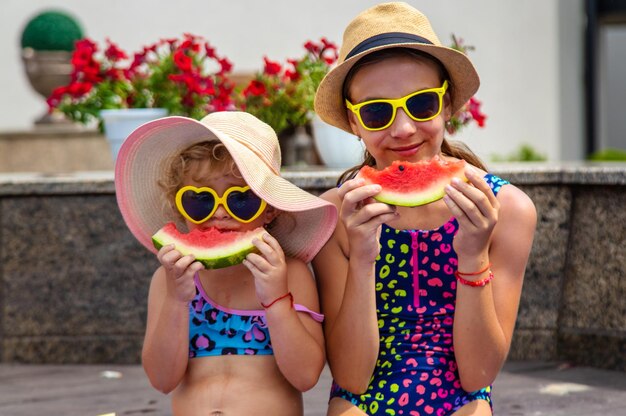 Photo les enfants mangent de la pastèque près de la piscine.