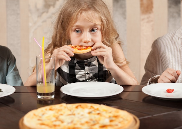 Les enfants mangent une pizza au restaurant.