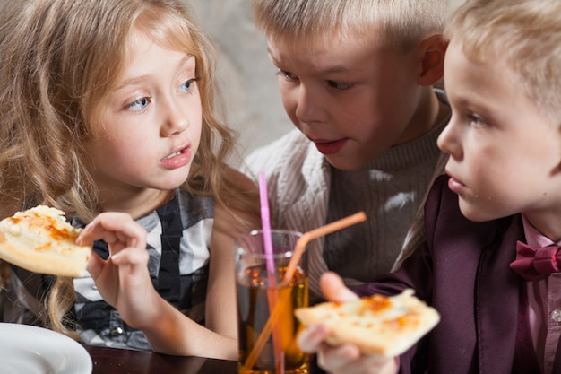 Les enfants mangent une pizza au restaurant.