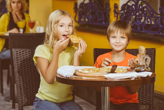 Les enfants mangent de la pizza et boivent du jus en plein air