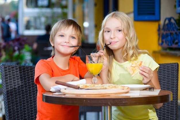 Les enfants mangent de la pizza et boivent du jus en plein air