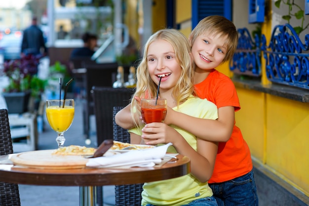 Les enfants mangent de la pizza et boivent du jus en plein air