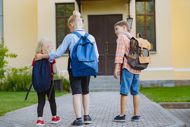 enfants marchant à l'école avec des sacs à dos par une journée ensoleillée. Début d'année universitaire. Les garçons par école font