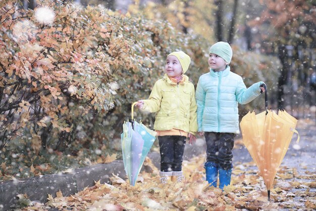 Les enfants marchent dans le parc avec la première neige