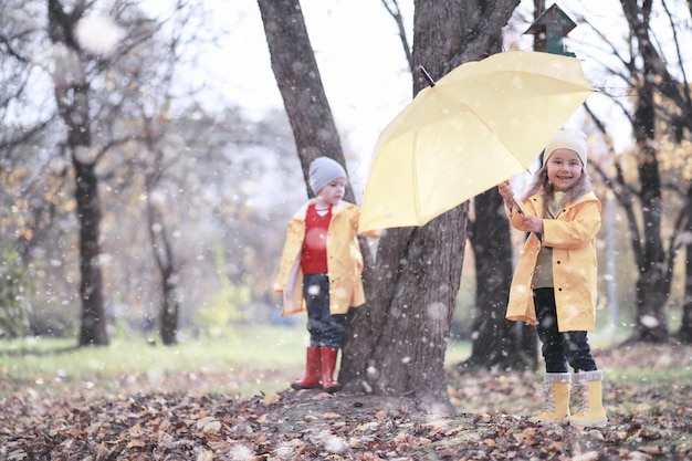 Les enfants marchent dans le parc avec la première neige