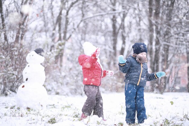 Les enfants marchent dans le parc avec la première neige