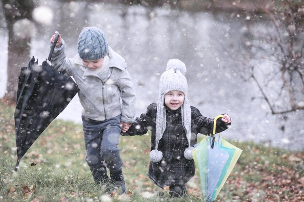 Les enfants marchent dans le parc avec la première neige