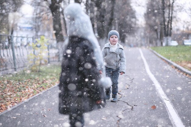 Les enfants marchent dans le parc avec la première neige