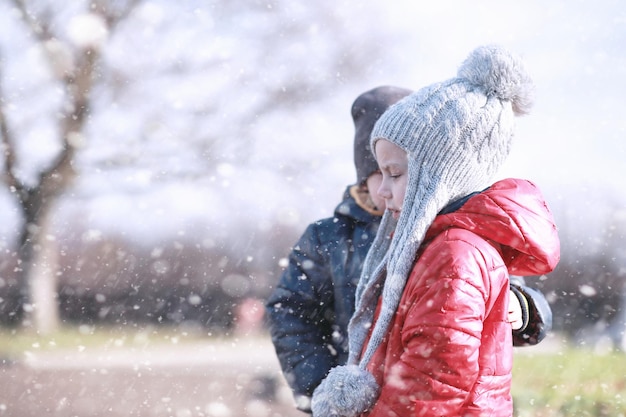 Les enfants marchent dans le parc avec la première neige