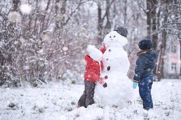 Les enfants marchent dans le parc avec la première neige