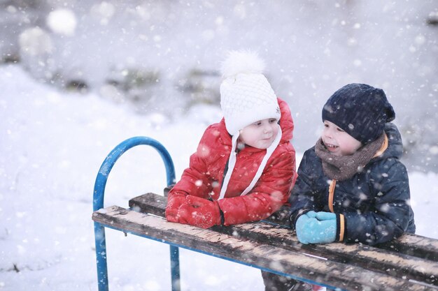 Les enfants marchent dans le parc avec la première neige