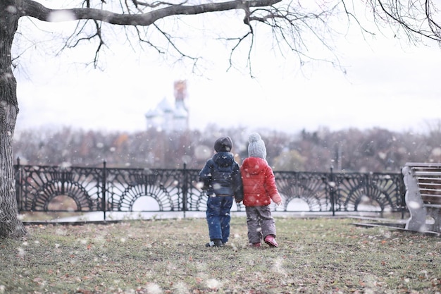 Les enfants marchent dans le parc première neige