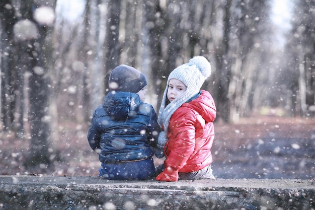 Les enfants marchent dans le parc première neige