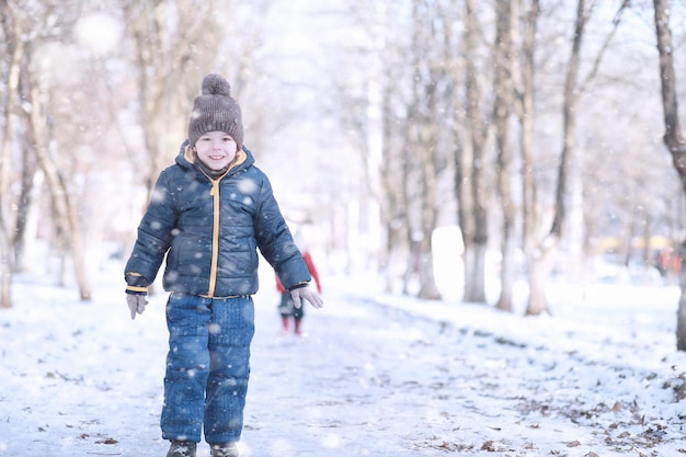 Les enfants marchent dans le parc première neige