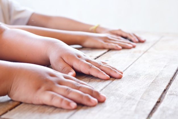 Photo les enfants mettent leurs mains sur la table en bois, concentrés sur la main gauche de la première personne.