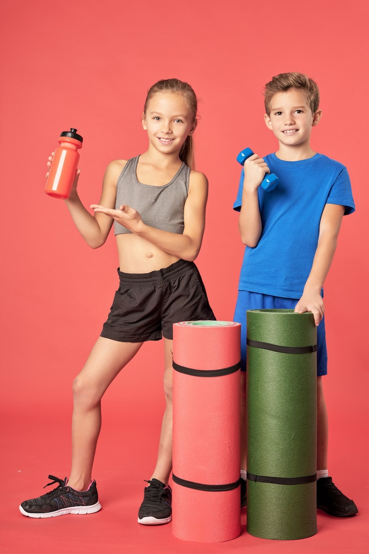 Photo enfants mignons avec équipement de sport debout sur fond rouge