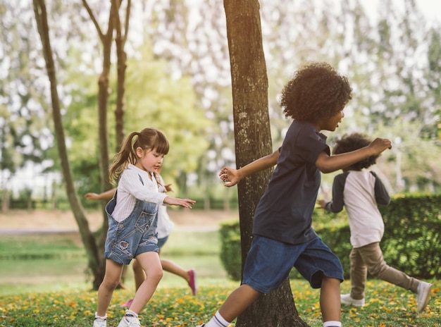 Photo des enfants mignons jouant autour des arbres dans le parc.