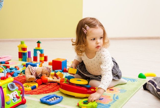 Des enfants mignons jouent à la maternelle. Un petit garçon s'intéresse au jouet de son ami