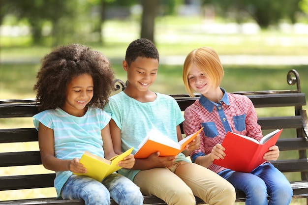 Enfants mignons lisant des livres sur un banc