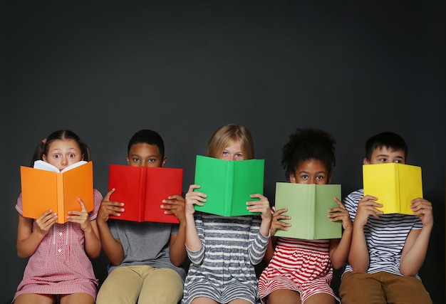 Enfants mignons lisant des livres sur fond gris