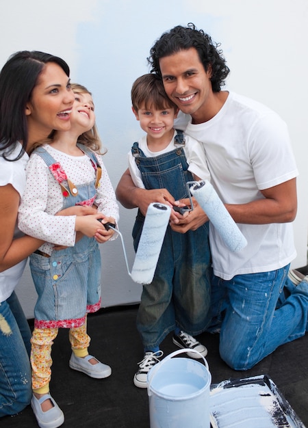 Des enfants mignons peignant une chambre avec leurs parents