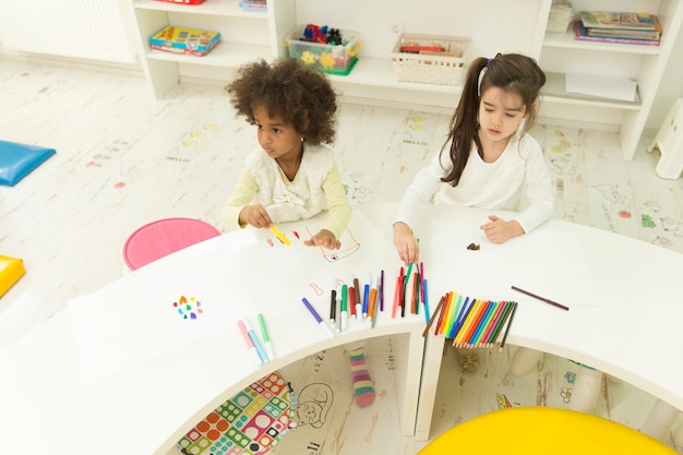 Photo enfants multiraciales dessinant dans la salle de jeux