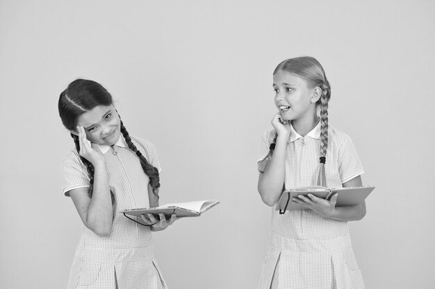 Enfants nerveux Enfants mignons lisant un livre sur fond jaune Adorables petites filles apprennent à lire l'espace de copie Lecture à la maison et scolarisation Étudier dur L'examen arrive Test final Sujet difficile