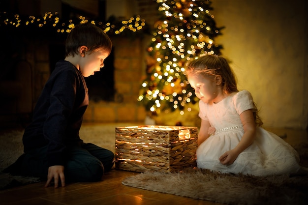 Les enfants ont ouvert un cadeau magique du Nouvel An dans un intérieur de Noël avec un arbre de Noël et des guirlandes