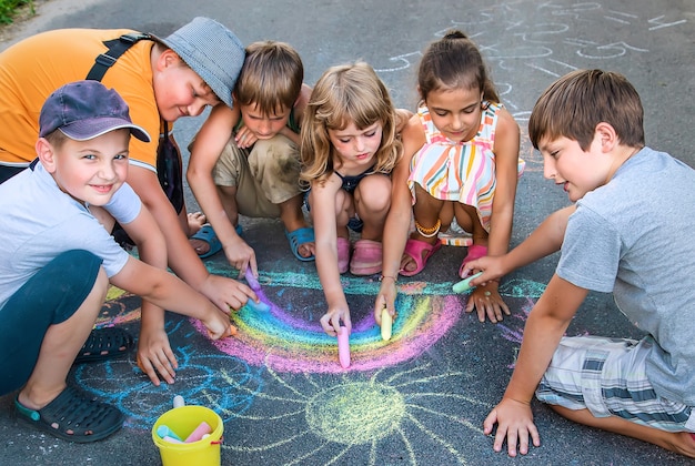 Les enfants peignent un arc-en-ciel sur l'asphalte. Mise au point sélective. Des gamins.