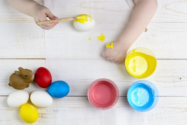 Les enfants peignent des œufs pour Pâques sur la table en bois