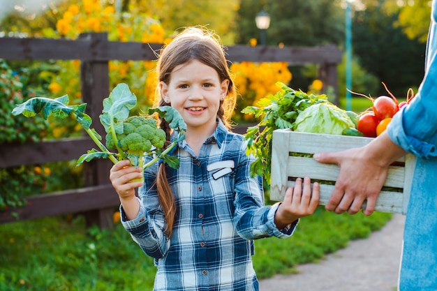 Enfants petite fille tenant maman un panier de légumes biologiques frais avec le jardin potager.