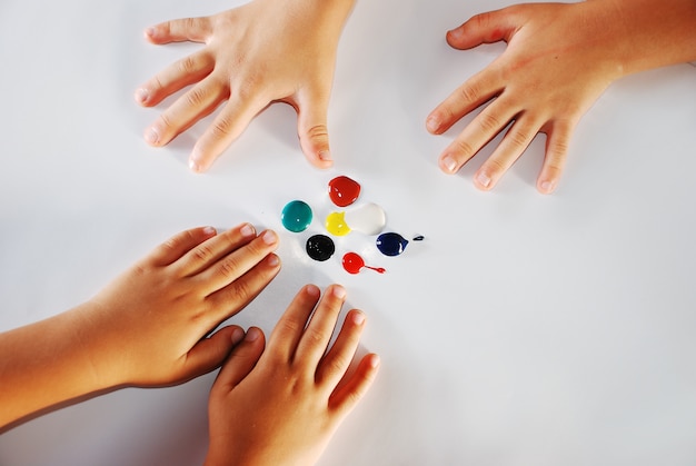 Enfants petites mains jouant avec des couleurs sur fond blanc