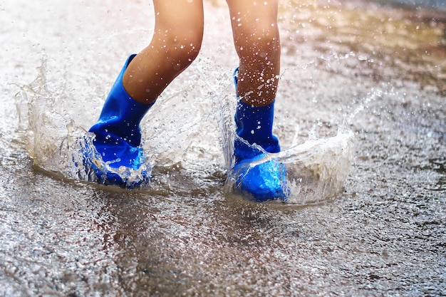 Enfants Portant Des Bottes De Pluie Et De Sauter Dans Une Flaque D'eau Le Jour De Pluie