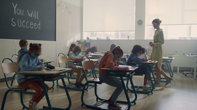 Des enfants portant des masques médicaux étudient ensemble en classe pendant la pandémie de coronavirus