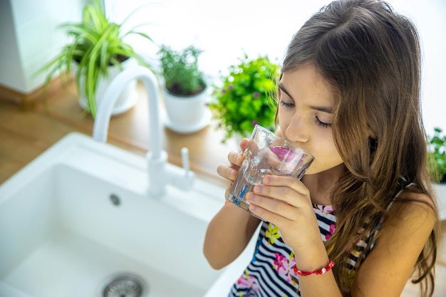 Les enfants prennent un verre d'eau du robinet. Mise au point sélective. Enfant.