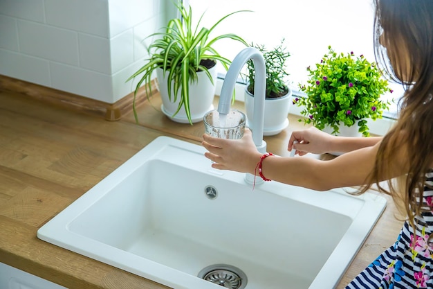 Les enfants prennent un verre d'eau du robinet. Mise au point sélective.