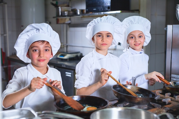 Enfants préparant le déjeuner dans une cuisine de restaurant.