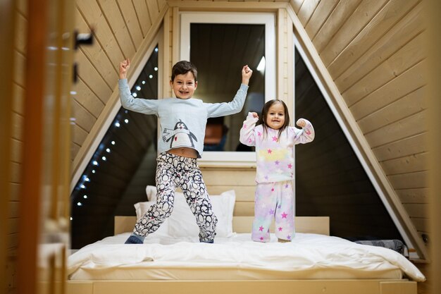 Enfants en pyjama doux et chaud jouant à la maison de la cabane en bois Concept de bonheur de l'activité de loisirs de l'enfance Frère et sœur s'amusant et jouant ensemble