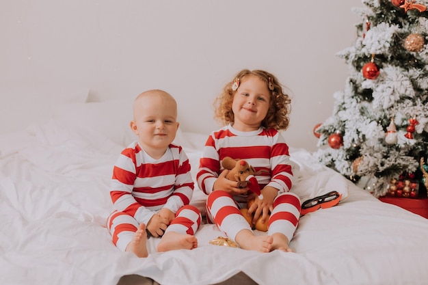 Les enfants en pyjama rouge et blanc jouent s'amusent à faire des grimaces dans le style de vie du lit