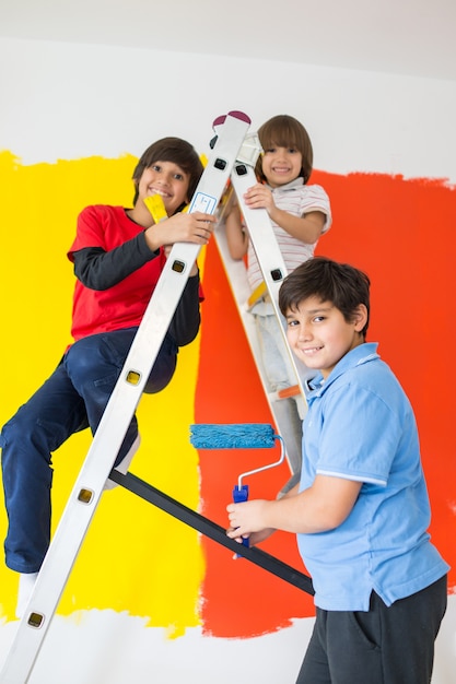 Enfants qui aident à peindre le mur à la maison