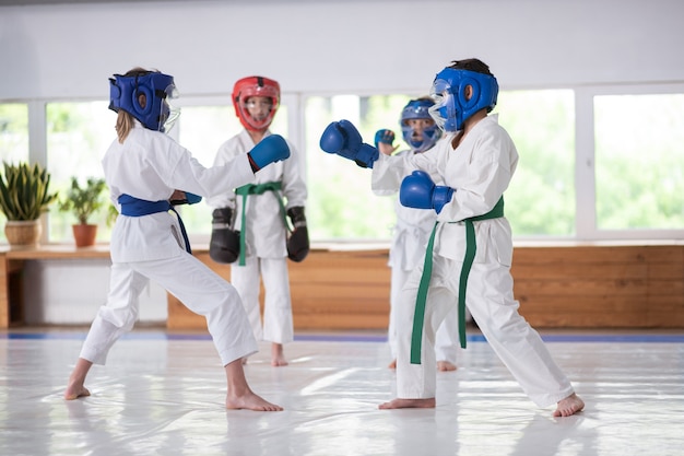 Les enfants qui étudient les arts martiaux portant des casques en boxe