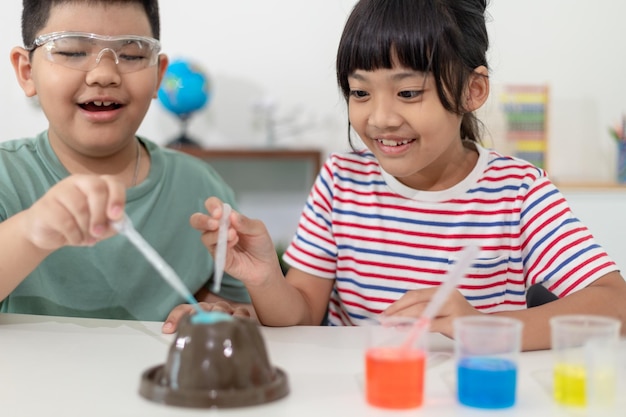 Enfants répétant et observant un projet de laboratoire scientifique à la maison le volcan de bicarbonate de soude et de vinaigre